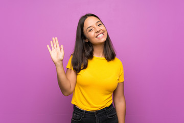 Young brunette girl over isolated background saluting with hand with happy expression © luismolinero