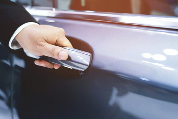 Close up image of a businessman hand on handle opening a car door. Service executive professional Pull the door to you. Leave space for the text to describe