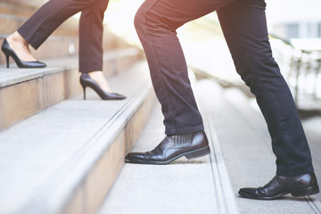 business man close-up legs walking up and working woman go down the stair in city. walk by in opposite directions in rush hour to work in office a hurry. During the first morning of work. stairway