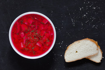 Top view of beetroot soup in white bowl on black background