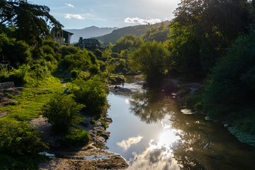 Scene view of sunset in the mountains reflecting sunlight on the river during summer season in La Cumbrecita, Cordoba, Argentina