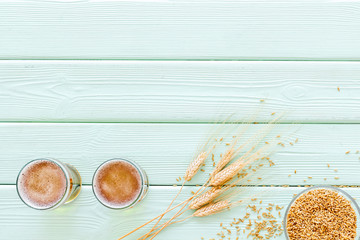 Obraz premium Beer ingredients. Barley near beer glasses on green wooden background top view copy space