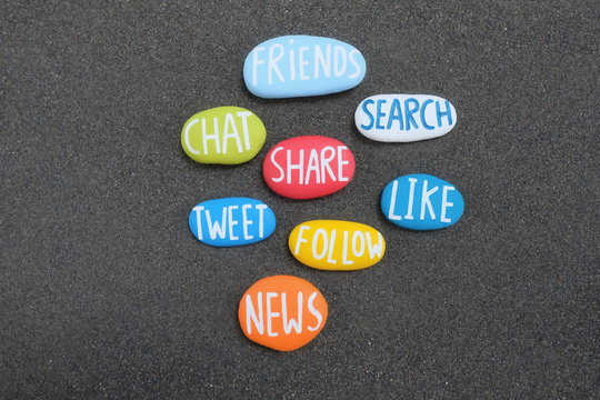 Social words composed with carved and multi colored stones over black volcanic sand