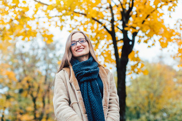 Woman standing on front of an autumn tree with colorful leaves