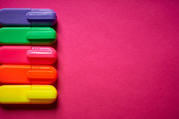 Close up of colorful markers on intense blurred pink background
