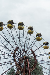 abandoned and rusty ferris wheel in green amusement park against blue sky