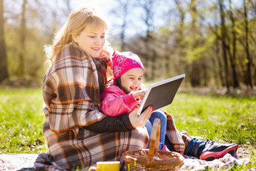 Mother and her daughter is playing with tablet, autumn