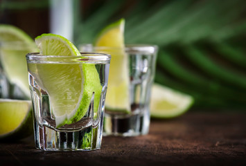 Cachaca - Brazilian strong alcoholic beverage from cane sugar, lime vodka, vintage wooden background, selective focus