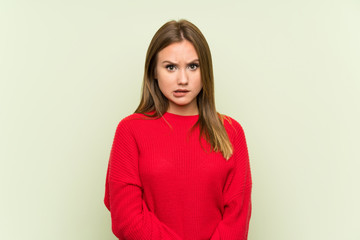 Teenager girl over isolated green background having doubts and with confuse face expression