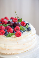 Homemade Pavlova cake with berries on the table in home interior.