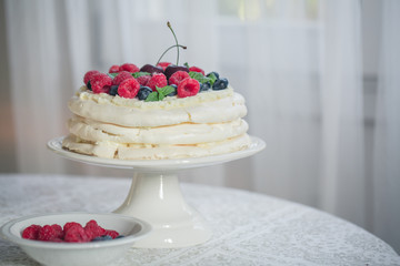 Homemade Pavlova cake with berries on the table in home interior.