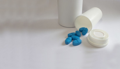 white bottle with caps and blue pills for diseased treatment, white background.