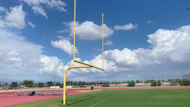 empty high school football field on beautiful day with blue sky and clouds