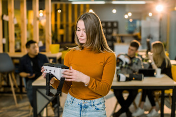 cheerful young woman adjusting her virtual reality headset while standing at her working place in office with relax.