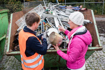 Woman putting scrap metal in container to be recycled