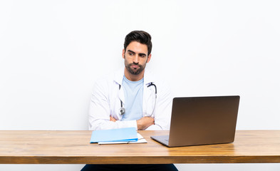 Young doctor man with his laptop over isolated wall thinking an idea