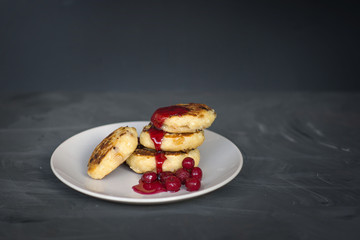 cottage cheese pancakes with cherries and jam on a dark background
