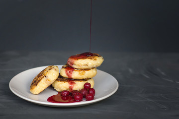 cottage cheese pancakes with cherries and jam on a dark background