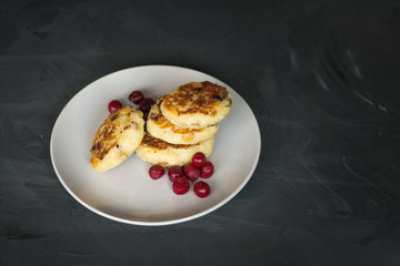 cottage cheese pancakes with cherries and jam on a dark background