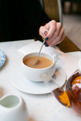 Woman stirring milk and sugar in tea