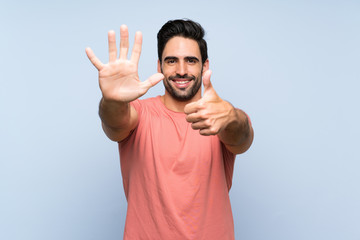 Fototapeta premium Handsome young man in pink shirt over isolated blue background counting six with fingers