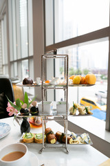Afternoon high tea at fancy hotel, assortment of dessert and savory finger foods