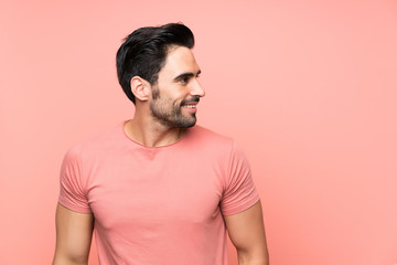 Handsome young man over isolated pink background looking to the side