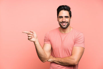 Handsome young man over isolated pink background pointing finger to the side