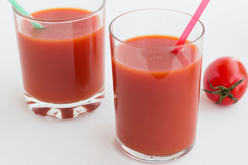 Two glasses of tomato juice on a white background