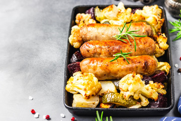 Sheet pan dinner, baked vegetables, turkey sausages. Selective focus, copy space.