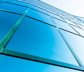 facade of modern office building in glass and steel with reflections of blue sky