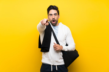 Young sport man over isolated yellow wall surprised and pointing front