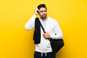 Young sport man over isolated yellow wall having doubts and with confuse face expression