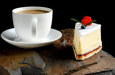 Fruit cake with cherries, grapes and plum stands on a wild stone next to a white cup of coffee with a foam