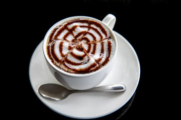 Hot art Mocha Coffee in a cup on black table. Image on top view.