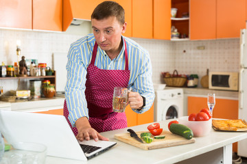 Man using laptop during cooking