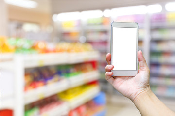 Female hand holding a smartphone with blank screen, blurred supermarket background.