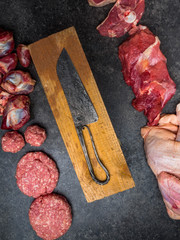 mixed types of raw fresh meat on cutting board with knife