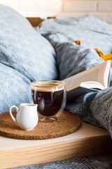 Black coffee in a transparent cup in bed in the autumn morning