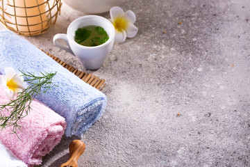 Color towels with flower, spoon of salt, on bamboo mat, bath spa treatment and green tea on stone table, copy space