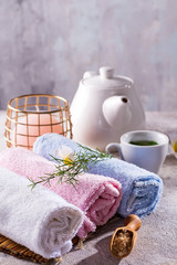 Color towels with flower, spoon of salt, on bamboo mat, bath spa treatment and green tea on stone table, copy space