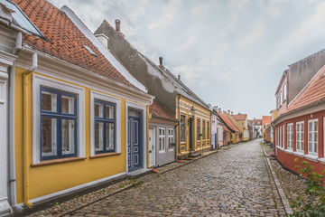 Fototapeta na wymiar an idyllic street with cobblestone and colourful houses on the beautiful island Aero, Denmark, July 13, 2019