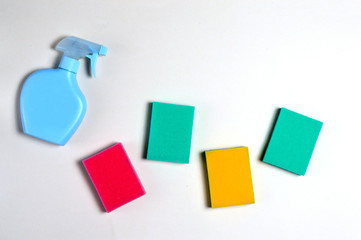 multi-colored washing sponges lie on a white surface next to the detergent container