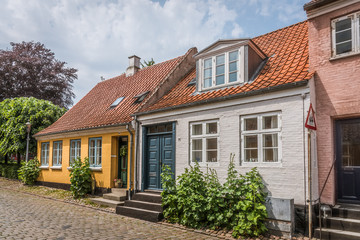 idyllic danish houses in retro style on a cobblestone street with hollyhochs