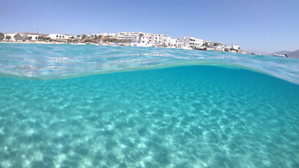 Above and below underwater photo of turquoise clear sea of Ammos sandy beach near port of Koufonisi island, Small Cyclades, Greece