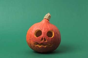 spooky Halloween pumpkin on green background