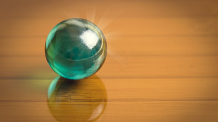 Dark green glass sphere on the reflect dark glass surface. Free place for your text or image. Abstract high resolution macro photography with 16:9 proportion useful for web design and decor.