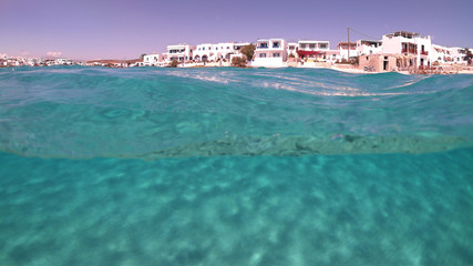 Fototapeta premium Above and below underwater photo of turquoise clear sea of Ammos sandy beach near port of Koufonisi island, Small Cyclades, Greece