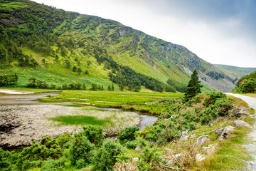 Idyllic view in Glendalough Valley, County Wicklow, Ireland. Mountains, lake and tourists walking...