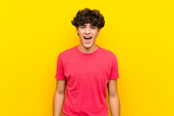 Young man over isolated yellow wall with surprise facial expression